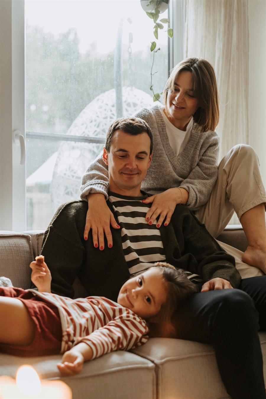 Une famille détendue sur un canapé, dans un intérieur propre et lumineux